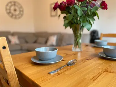 a wooden table with two bowls and a vase of flowers at Cardonald Central in Glasgow