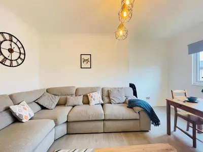 a living room with a couch and a clock on the wall at Cardonald Central in Glasgow