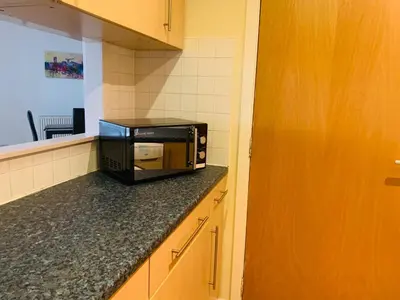 a microwave sitting on top of a counter in a kitchen at Modern 2 Bed Apartment, Close to Gla Airport & M8 in Paisley