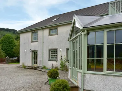 a white house with a large glass door at Stronafian House in Feorlean