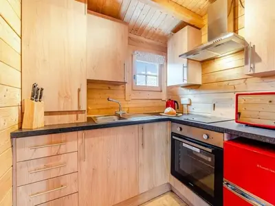 a kitchen with wooden cabinets and a sink and a stove at Lochinvar - Clydesdale Log Cabin with Hot Tub in Airdrie