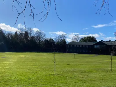 two trees in a field with a building in the background at Gleneagles Luxury Apartments in Auchterarder