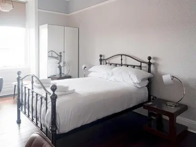 a bedroom with a bed with white sheets and a mirror at Beautiful, traditional 2 bed flat w free parking - Pass the Keys in Glasgow