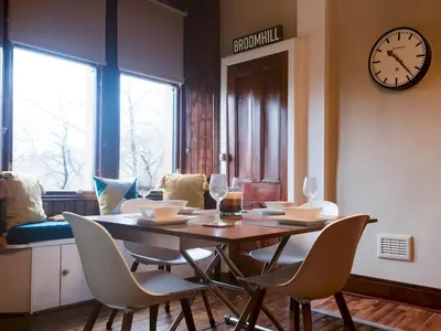 a dining room with a table and chairs and a clock at Beautiful, traditional 2 bed flat w free parking - Pass the Keys in Glasgow