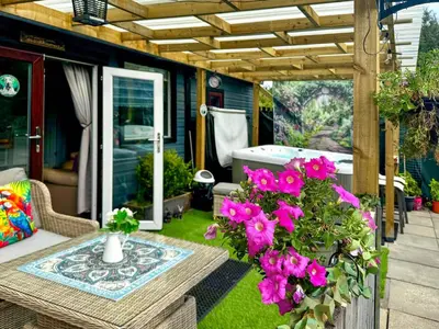 a patio with pink flowers and a table at Bumbles Barn in Slamannan