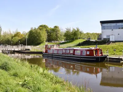 a red boat is docked on a river at Bumbles Barn in Slamannan