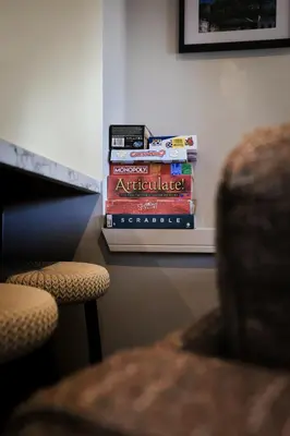 a stack of books sitting on a shelf next to a chair at The White City Apartment in Oban