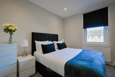 a bedroom with a large bed and a window at The White City Apartment in Oban