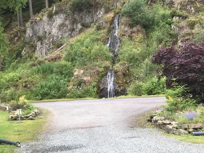 a road with a waterfall on the side of a mountain at The Wimbledon 70 in Dunoon