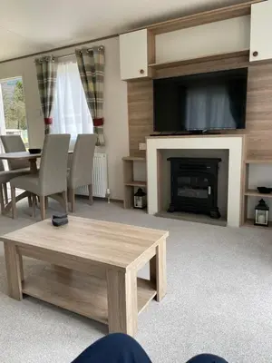 a living room with a table and a fireplace with a tv at The Wimbledon 70 in Dunoon