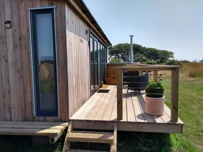 a wooden deck next to a house with a plant at Cleeves Cabins Ailsa Luxury Lodge with hot tub in Dalry