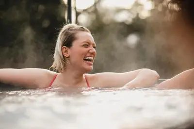 a woman laughing in a hot tub at Cleeves Cabins Ailsa Luxury Lodge with hot tub in Dalry