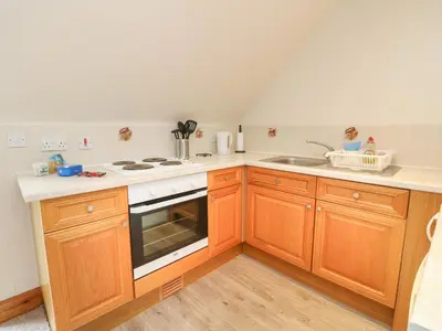 a kitchen with wooden cabinets and a stove top oven at MacKintosh in Pitlochry