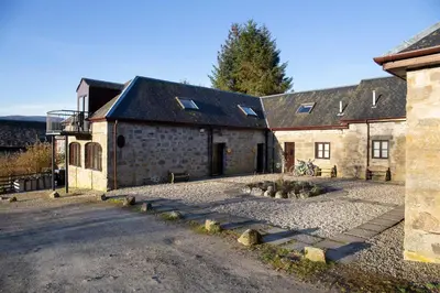 an old stone building with a driveway in front of it at MacKintosh in Pitlochry