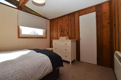 a bedroom with a bed and a dresser and a window at Musselshell Lodge in Otter Ferry