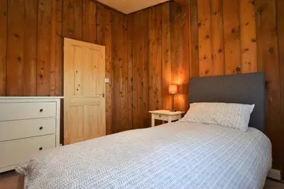 a bedroom with a bed and a dresser and a lamp at Scallopshell Lodge in Otter Ferry