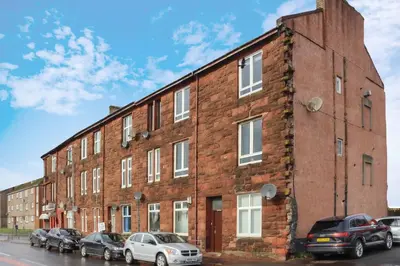 a brick building with cars parked in front of it at Townend Apartment in Dumbarton