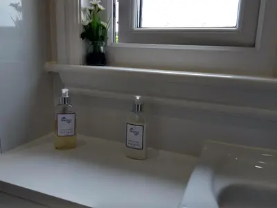 two bottles sitting on a counter next to a sink at Cleeves Cabins Arran Luxury Lodge with hot tub in Dalry