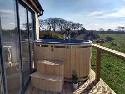 a hot tub on the deck of a house at Cleeves Cabins Arran Luxury Lodge with hot tub in Dalry