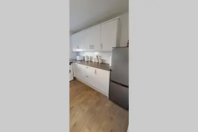 a kitchen with white cabinets and a stainless steel refrigerator at Craiglynn Holiday Apartment Loch Lomond in Balloch
