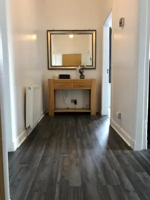 a hallway with a mirror and a wooden floor at Premier Apartment C in Broxburn