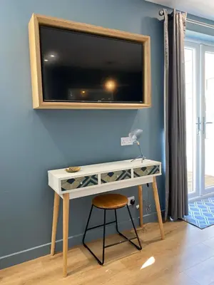 a desk with a television on a blue wall at Lynwood Studio in Oban