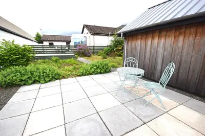 a patio with two chairs and a table and a fence at Arivean Cottage in Lochgoilhead