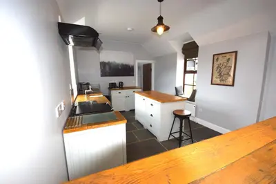 a kitchen with white cabinets and a counter top at Arivean Cottage in Lochgoilhead