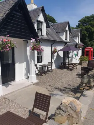 a house with a bench and a red phone booth at Ardeonaig Hotel & Restaurant in Ardeonaig
