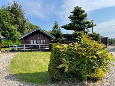 a house with a tree in front of a yard at Wellsfield Farm Holiday Lodges in Stirling