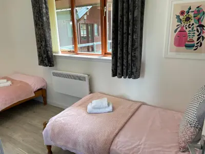 a bedroom with two beds and a window at Wellsfield Farm Holiday Lodges in Stirling