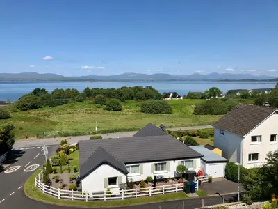 an aerial view of a house with a lake in the background at Brecbennoch in Oban