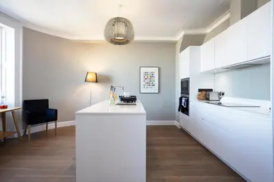 a kitchen with a white counter and a chair at JOIVY Splendid Apartment in New Town in Edinburgh