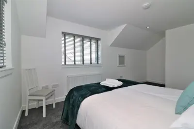 a white bedroom with a bed and a chair at Signature - Railway House 5 bed in Maryhill