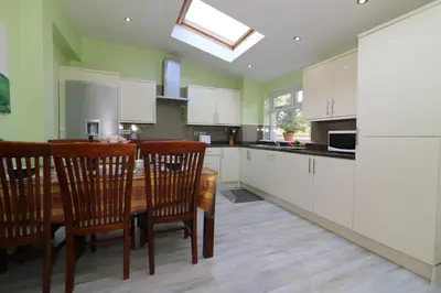 a kitchen with white cabinets and a wooden table and chairs at Signature - Dumbreck House in Glasgow