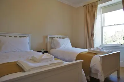 a bedroom with two beds with white sheets and a window at 136 West Princes Street in Helensburgh