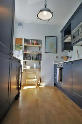 a kitchen with blue cabinets and a table and a chair at 136 West Princes Street in Helensburgh