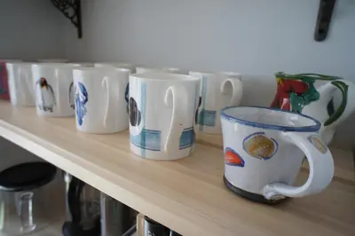 a row of coffee cups sitting on a shelf at 136 West Princes Street in Helensburgh
