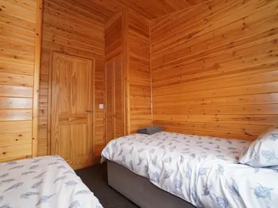 a bedroom with two beds and a wooden wall at Chalet Loch Leven Lodge 11 by Interhome in Kinross