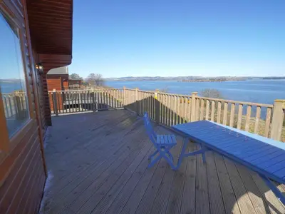 a blue picnic table on a deck with a view of the water at Chalet Loch Leven Lodge 11 by Interhome in Kinross