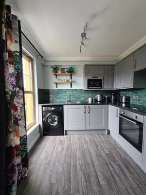 a kitchen with white cabinets and a washing machine at EDEN Apartment, Oban in Oban