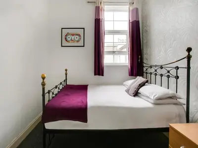 a bedroom with a bed with purple sheets and a window at OYO Gin House Hotel in Greenock