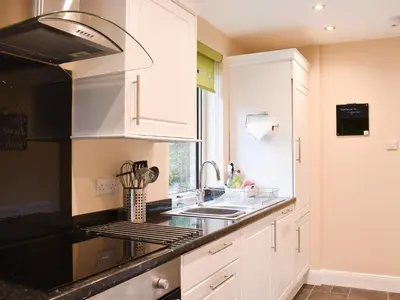 a kitchen with white cabinets and black counter tops at Ingleside in Whiting Bay