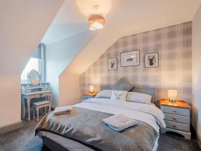 a bedroom with a bed and a desk and a window at Harbour View House in Girvan