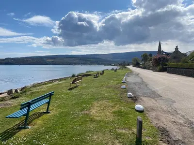a row of park benches on the side of a lake at Lamlash- Self catering accommodation with seaviews in Lamlash
