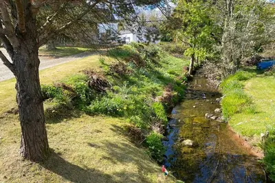 a stream of water in a field with a tree at Lamlash- Self catering accommodation with seaviews in Lamlash