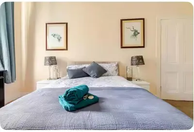 a bed with a blue blanket and a hat on it at 3 Bed Central Apartment - Pet Friendly & Parking in Edinburgh