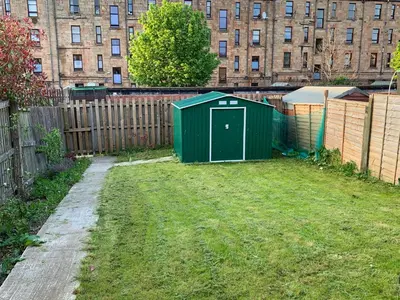 a green shed in a yard next to a fence at Dada House in Glasgow