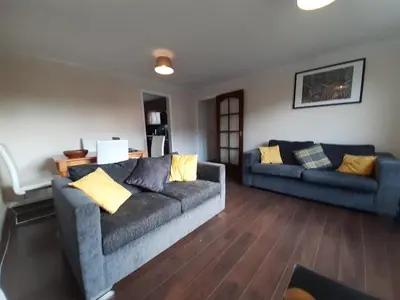 a living room with two couches and wooden floors at Carvetii - Stuart House - 1st floor flat sleeps up to 8 in Falkirk