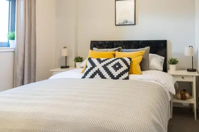 a bedroom with a white bed with yellow pillows at Luxury Riverview City Centre Apartment in Glasgow